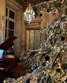 a decorated christmas tree in front of a grand piano