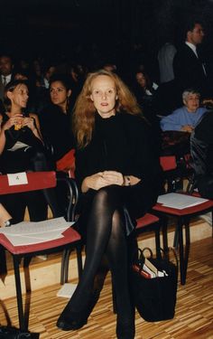 a woman sitting on a red chair in front of an audience with her legs crossed