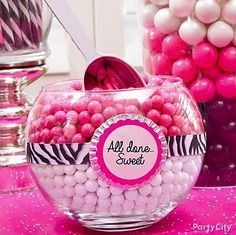 pink and white candy balls in a glass bowl with an all one sweet tag on it