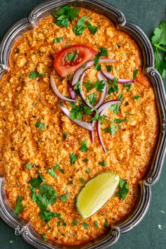 an enchilada dish with onions, tomatoes and cilantro on the side