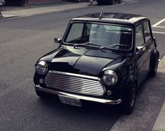 an old black car is parked on the side of the road