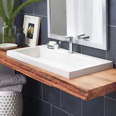 a bathroom sink sitting under a mirror on top of a wooden counter next to a plant