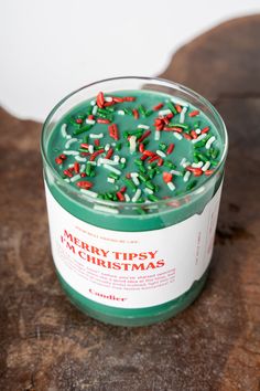 a green candle with sprinkles in it sitting on a wooden table next to a piece of wood