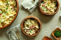 three wooden bowls filled with different types of pasta and garnished with parsley