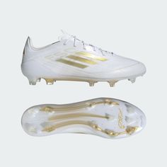 a white soccer shoe with gold detailing on the top and bottom, in front of a white background