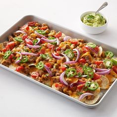 a tray filled with taco salad next to a bowl of guacamole