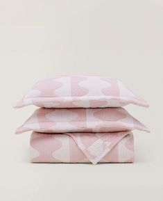 three pillows stacked on top of each other in pink and white hearts print, with one pillow folded up to the side