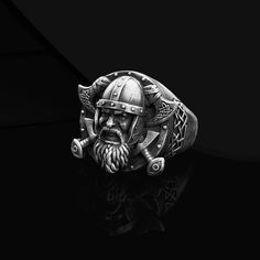 a ring with an image of a viking on it's face and two swords in his hand