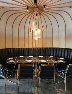 a round table with black leather chairs around it and a chandelier hanging from the ceiling