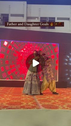 two people standing on a stage in front of a red and white screen with the words father and daughter goals