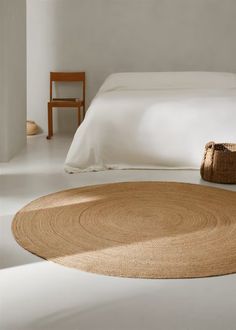 a bedroom with white walls and an oval rug on the floor next to a bed