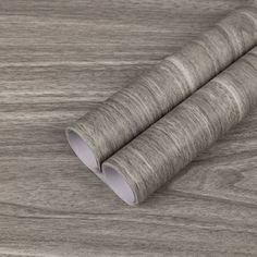 two rolls of grey paper sitting on top of a wooden table