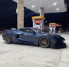 a blue sports car parked in front of a gas station