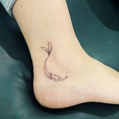 a small tattoo on the foot of a woman's leg, with a whale tail