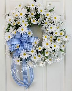 a blue and white wreath with daisies hanging on a door