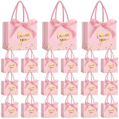 pink gift bags with gold foil lettering on them and bows tied around the handles that say thank you