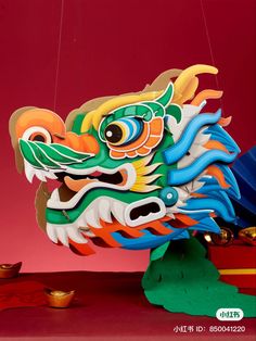 a colorful dragon head hanging from a string on a red wall with other decorations around it