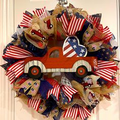 a patriotic wreath with an old red truck and american flags on the front door for fourth of july