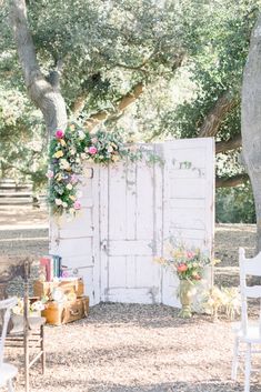 an old door is decorated with flowers and greenery for a wedding ceremony in the woods