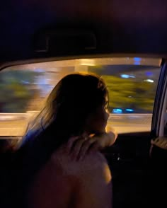 a woman sitting in the back seat of a car talking on her cell phone at night