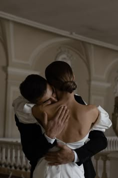 a bride and groom embrace in front of a staircase