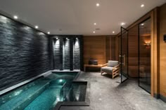 an indoor swimming pool in the middle of a room with stone walls and flooring