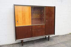 a wooden cabinet sitting next to a white brick wall on the side of a road