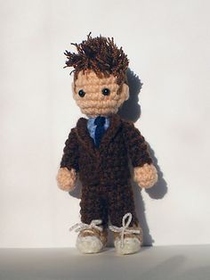 a crocheted doll is dressed in a brown suit and tie with white shoes