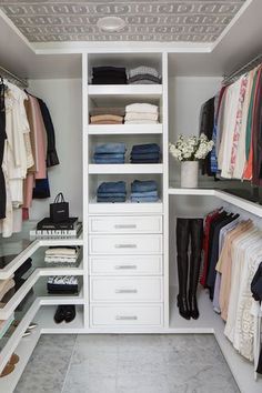 an organized closet with clothes and shoes on the shelves, along with other items in it