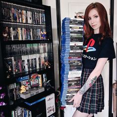 a woman standing in front of a book shelf filled with movies and dvds, holding her hand on her hip