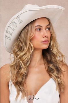 a woman wearing a white cowboy hat with the word bride on it's side