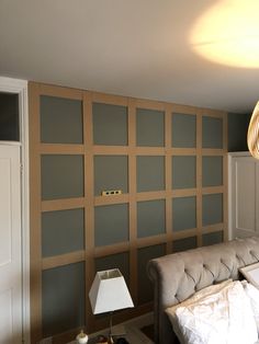 a living room with a couch, lamp and wall paneled in wood panels on the walls