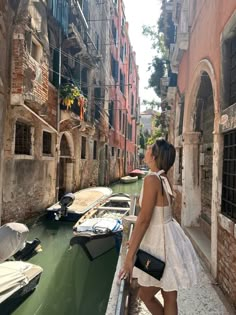 a woman is standing on the edge of a canal