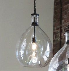 two clear glass pendant lights hanging from a brick wall