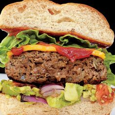 a large hamburger with lettuce, tomato and onion on a white bread bun