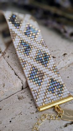 a close up of a bracelet on a stone surface with a gold chain attached to it