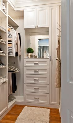 a walk in closet with white cabinets and drawers