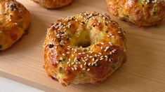 several bagels with sesame seeds are on a cutting board and ready to be eaten