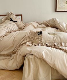 an unmade bed with ruffled sheets and pillows