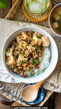 a bowl filled with rice and meat on top of a wooden table