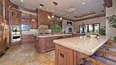 a large kitchen with marble counter tops and wooden cabinets, along with an island in the middle