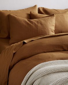 a bed covered in brown sheets and pillows