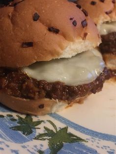 two hamburgers with cheese and meat on a blue and white plate, one is cut in half