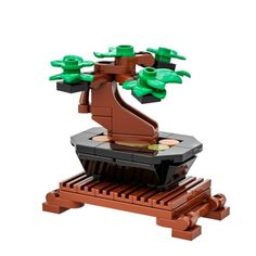 a lego tree is sitting on top of a wooden pallet and has green leaves growing out of it