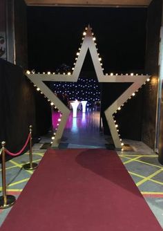 a red carpeted walkway leading to a star with lights on the sides and an arch in the middle