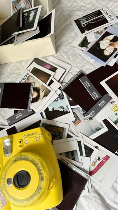 a yellow camera sitting on top of a bed covered in pictures