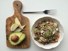 an avocado and rice salad on a wooden cutting board next to a fork