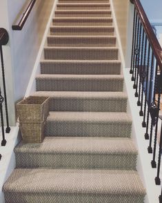 a carpeted stair case with a basket on the bottom