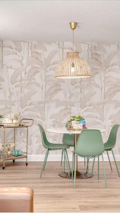 a dining room table and chairs in front of a wall papered with palm leaves