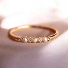 a gold ring with five pearls on it sitting on a white cloth covered tablecloth